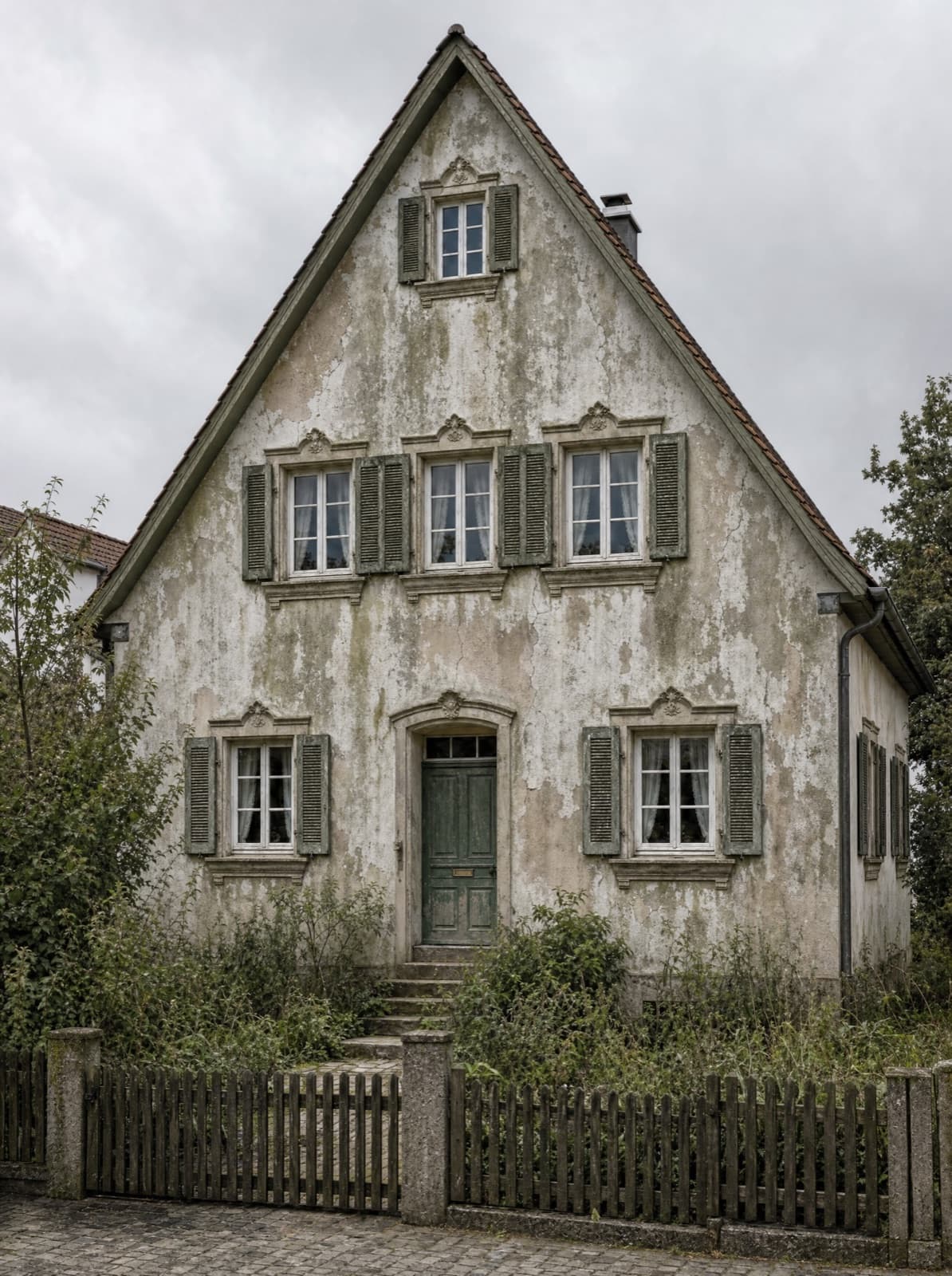 Altbau vor der Sanierung — verwitterter Putz, Risse, vergilbter Anstrich, verwitterte Fensterläden